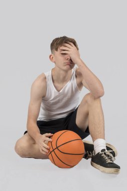 Kafkasyalı genç çocuk basketbol oynarken üzgün görünüyor.