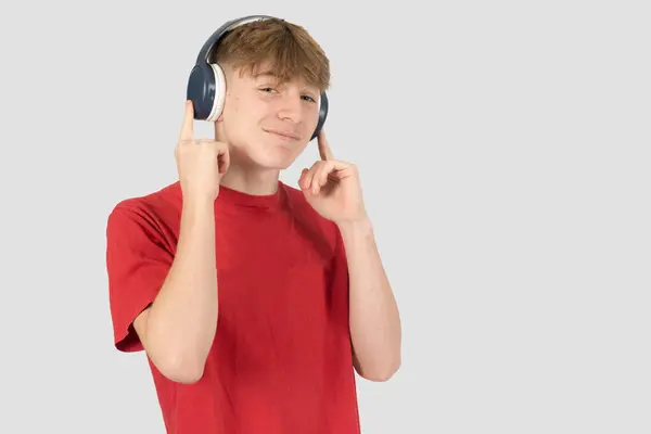 stock image Caucasian 15 year old teenage boy, wearing a red t-shirt,  listening to music via headphones and smiling