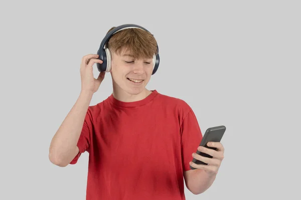 Stock image Teenage boy listening to music via wireless headphones from his mobile phone