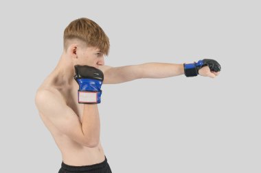 Üstsüz genç erkek MMA dövüşçüsü yumrukluyor.