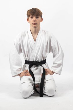 Seiza 'da diz çökmüş, A Gi giyen 15 yaşındaki Karate Blackbelt çocuğu.