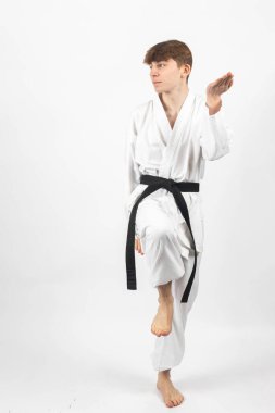 15 yaşında bir Karate Siyah Kemeri çocuğu, A Gi giyip kata yapıyor.