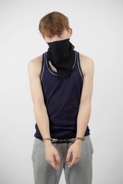 Maske takan, kelepçeli bir ergen çocuk.