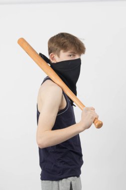 Beyzbol sopası tutan maskeli genç bir çete üyesi.