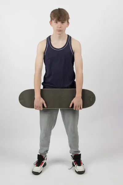 Femton Gammal Åkare Pojke Som Håller Skateboard Mot Vit Bakgrund Royaltyfria Stockfoton