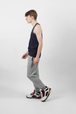 Kas yelekli beyaz bir arka planda duran on beş yaşındaki bir genç çocuk...