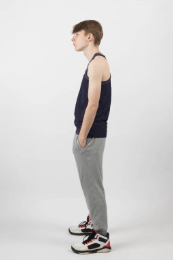 Kas yelekli, cebinde Hamps olan beyaz bir arka planda duran on beş yaşında bir çocuk.