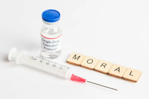 stock image A Medical Vial with a label reading Single Drug Execution Protocol with a sign reading Moral, and a Syringe