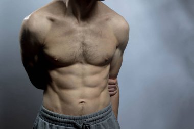 Karın kasları ve göğsü iyi tanımlanmış genç bir erkek cesedi. Gömleksiz gövdeli bir model. Vücut bakımı, erkek sağlığı, fitness, gençlik, erkeklik, sağlık, kilo kaybı, vücut geliştirme 