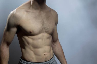 Karın kasları ve göğsü iyi tanımlanmış genç bir erkek cesedi. Gömleksiz gövdeli bir model. Vücut bakımı, erkek sağlığı, fitness, gençlik, erkeklik, sağlık, kilo kaybı, vücut geliştirme 