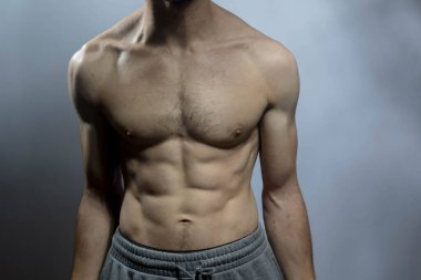 Karın kasları ve göğsü iyi tanımlanmış genç bir erkek cesedi. Gömleksiz gövdeli bir model. Vücut bakımı, erkek sağlığı, fitness, gençlik, erkeklik, sağlık, kilo kaybı, vücut geliştirme 