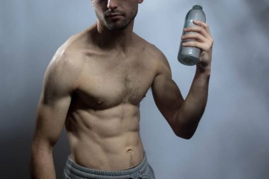 Karın kasları ve göğsü iyi tanımlanmış genç bir erkek cesedi. Gömleksiz gövdesi olan bir şişe su tutan manken. Vücut bakımı, erkek sağlığı, fitness, gençlik, erkeklik, sağlık, kilo kaybı, vücut geliştirme 