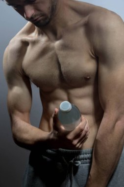 Karın kasları ve göğsü iyi tanımlanmış genç bir erkek cesedi. Gömleksiz gövdesi olan bir şişe su tutan manken. Vücut bakımı, erkek sağlığı, fitness, gençlik, erkeklik, sağlık, kilo kaybı, vücut geliştirme 
