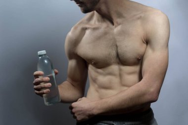 Karın kasları ve göğsü iyi tanımlanmış genç bir erkek cesedi. Gömleksiz gövdesi olan bir şişe su tutan manken. Vücut bakımı, erkek sağlığı, fitness, gençlik, erkeklik, sağlık, kilo kaybı, vücut geliştirme 