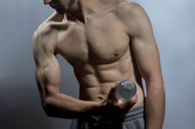 Karın kasları ve göğsü iyi tanımlanmış genç bir erkek cesedi. Gömleksiz gövdesi olan bir şişe su tutan manken. Vücut bakımı, erkek sağlığı, fitness, gençlik, erkeklik, sağlık, kilo kaybı, vücut geliştirme 