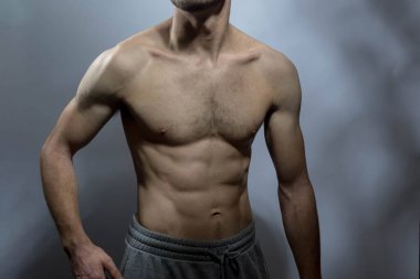 Karın kasları ve göğsü iyi tanımlanmış genç bir erkek cesedi. Gömleksiz gövdeli bir model. Vücut bakımı, erkek sağlığı, fitness, gençlik, erkeklik, sağlık, kilo kaybı, vücut geliştirme 