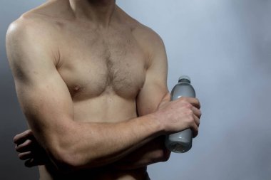 Karın kasları ve göğsü iyi tanımlanmış genç bir erkek cesedi. Gömleksiz gövdesi olan bir şişe su tutan manken. Vücut bakımı, erkek sağlığı, fitness, gençlik, erkeklik, sağlık, kilo kaybı, vücut geliştirme 