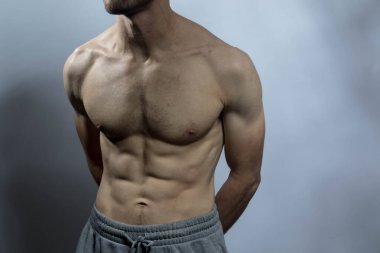Karın kasları ve göğsü iyi tanımlanmış genç bir erkek cesedi. Gömleksiz gövdeli bir model. Vücut bakımı, erkek sağlığı, fitness, gençlik, erkeklik, sağlık, kilo kaybı, vücut geliştirme 