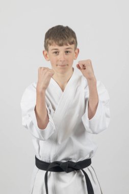 Fifteen year old male teenage karate black belt doing a Uraken Uchi, studio shot against a white background clipart