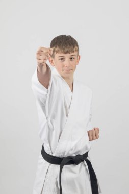 On beş yaşında, erkek, karate kara kuşağı. Yan yumruk atıyor. Stüdyo, beyaz bir arka plana karşı.