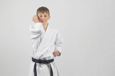 Fifteen year old male teenage karate black belt performing a rising elbow strike, studio shot against a white background clipart