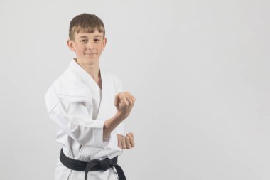 On beş yaşında, erkek, karate siyah kuşağı. Dış blok gösterisi yapıyor. Stüdyo, beyaz bir arkaplana karşı.