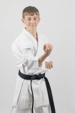 On beş yaşında, erkek, karate siyah kuşağı. Dış blok gösterisi yapıyor. Stüdyo, beyaz bir arkaplana karşı.