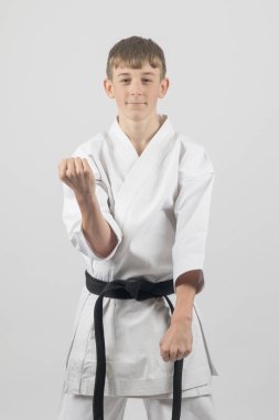 On beş yaşında, erkek, karate siyah kuşağı var. Çift blok yapıyor. Stüdyo çekimi beyaz arka planda.