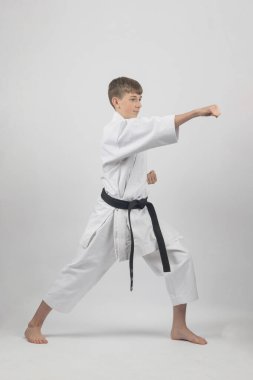 15 yaşında, erkek, karate siyah kuşağı var. Kafasına yumruk atıyor. Stüdyo çekimlerini beyaz arka planda yapıyor.