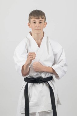 On beş yaşında, erkek, karate siyah kuşağı var. Stüdyo, beyaz bir arka plana karşı çekim yapıyor.