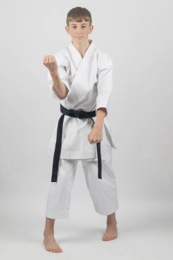 On beş yaşında, erkek, karate siyah bel Sanchin duruşu yapıyor. Çift blok yapıyor. Stüdyo çekimi beyaz arka planda.