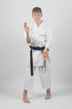 15 yaşında, erkek, karate, siyah bel. Sanchin duruşu yapıyor. Açık el bloğu yapıyor. Stüdyo çekimleri beyaz arka planda.