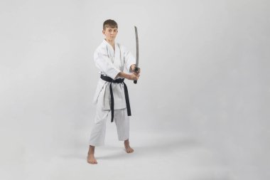 On beş yaşında, erkek, karate siyah kuşağı var. Stüdyoda beyaz bir arka plana karşı çekim yapıyor.
