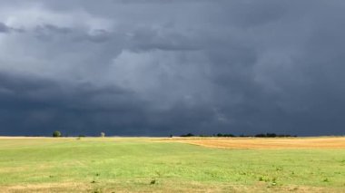 Kara bulutlar altında fırtınadan önce sonbahar tarlası ve köy üzerindeki tozlu patikanın kısa videosu. Fulda Hessen Almanya yakınlarında. Yüksek kaliteli FullHD görüntüler