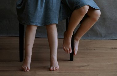 İçeride sandalyede oturan mavi elbiseli iki küçük kız kardeşin dört küçük bacağı. Yüksek kalite fotoğraf