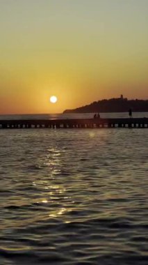 Gün batımında iskele silueti ve ufukta dağlarla birlikte. Kusadasi, Tuerkiye, Ege sahillerindeki deniz dalgaları. Peyzaj videosu. Yüksek kalite 4k görüntü