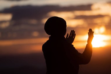 Gün batımında dua eden, dua eden, dua eden Müslüman bir kadın silueti. Yüksek kalite fotoğraf