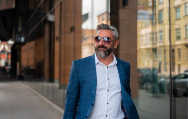 Şık giyimli, mutlu, olgun bir adam şehir caddesinde yürüyor. Yüksek kalite fotoğraf