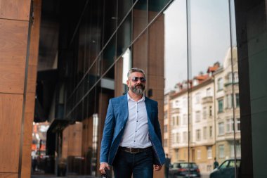 Şık giyinmiş olgun bir adam şehir caddesinde yürüyor. Yüksek kalite fotoğraf