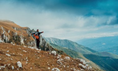 Erkek bir tırmanıcı, kollarını kaldırıp dağın tepesindeki başarılı rotasını kutluyor. Macera yolculuğu. Yüksek kalite fotoğraf