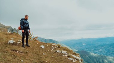 Yürüyüş sırasında dağın tepesinde duran bir erkek gezgin, macera yolculuğu. Yüksek kalite fotoğraf