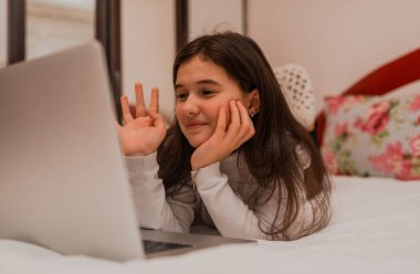 Evdeki kanepede rahatça otururken dizüstü bilgisayar kullanan mutlu bir genç kız. Yüksek kalite fotoğraf