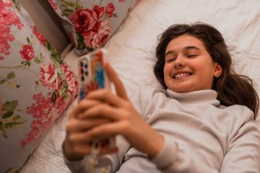 Evdeki kanepede rahatça otururken dizüstü bilgisayar kullanan mutlu bir genç kız. Yüksek kalite fotoğraf