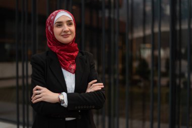 Modern ofis binasının yanında duran tesettürlü genç, kendinden emin Müslüman bir iş kadınının portresi. Yüksek kalite fotoğraf