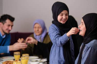Müslüman bir aile, Ramazan ayında oruç tutmak için iftar duası yapıyor mutlu ebeveynler, çocuklarıyla ve büyükanneleriyle evde yemek yiyorlar. Yüksek kalite fotoğraf