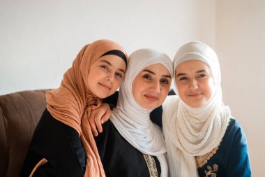 Evde mutlu bir Müslüman ailenin portresi, tesettürlü genç bir anne ve iki çocuk anne kameraya bakıyor ve Anneler Günü 'nde gülümsüyor. Yüksek kalite fotoğraf