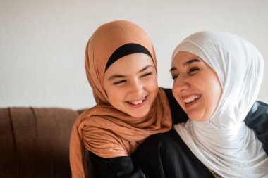 Mutlu Müslüman bir aile, anneler gününde anneler gününde şefkat göstermek için kanepede sevgiyle sarılıp birlikte oynuyorlar. Yüksek kalite fotoğraf