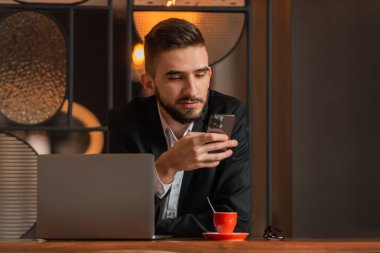 Ofisteki masasında oturan ve telefon kullanan genç mutlu iş adamının portresi. Yüksek kalite fotoğraf