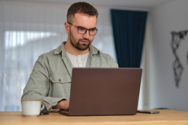 Evde çalışırken dizüstü bilgisayar kullanan genç bir adam. Yüksek kalite fotoğraf