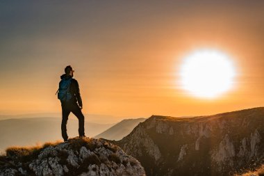 Yürüyüşe çıkan bir adam gün batımı macera yolculuğunda dağın tepesine bakmaktan zevk alır. Yüksek kalite fotoğraf